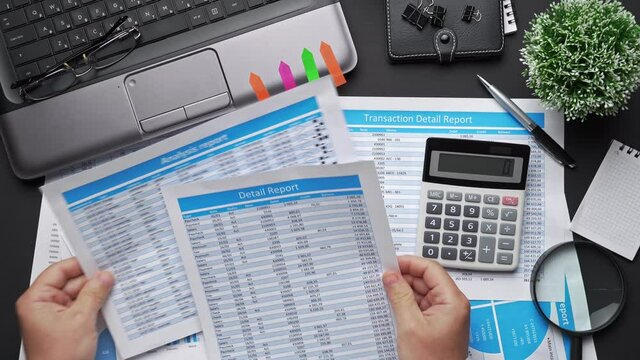 Top view of businessman working with financial statements. Modern black office desk with notebook, calc, pen and a lot of things. Flat lay table layout.
