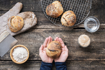 Top view of male hand holding freshly baked homemade bread bun