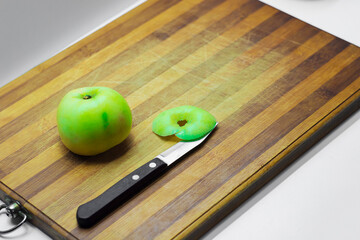 green Apple whole and slices on a wooden Board, knife with a wooden handle