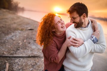 couple have fun during a beautiful evening by the river during sunset