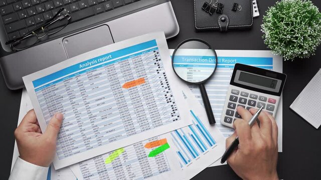 Top view of businessman working with financial statements. Modern black office desk with notebook, calc, pen and a lot of things. Flat lay table layout.
