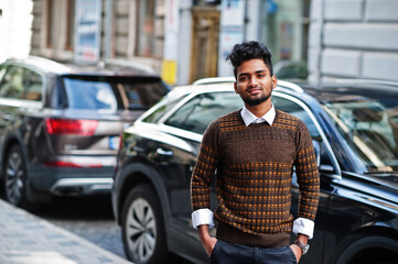 Portrait of young stylish indian man model pose in street against suv car.