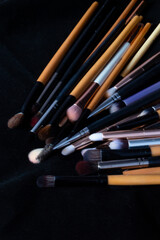 top view of many makeup brushes of various colors, on a black background