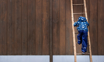 Child is standing on wooden step ladder. Child climbs up. Kind steht auf hölzerner Trittleiter. Kind klettert nach oben. 