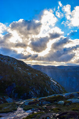Fototapeta na wymiar Gorgeous sunbeams pass through the clouds illuminating the mountain range where the path to Kjeragbolten lies. Norway