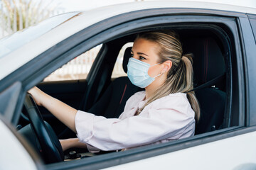  Woman with face mask driving her car during coronavirus pandemic