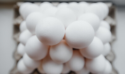 A tray of white fresh eggs in close-up laid out by a pyramid on a cardboard package. Agricultural industry