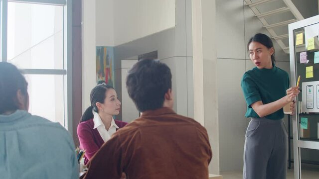Group of Asia young creative people meeting brainstorming ideas conducting business presentation ideas mobile application software design project colleagues in modern office. Coworker teamwork concept