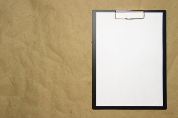 A tablet with a white sheet of A4 format on a beige craft paper.