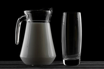 jug of milk and a glass on a black background