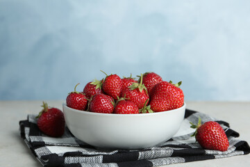 Delicious ripe strawberries in bowl on table