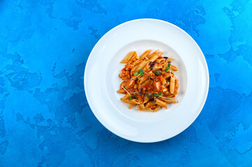 Tasty pasta in big white plate blue background