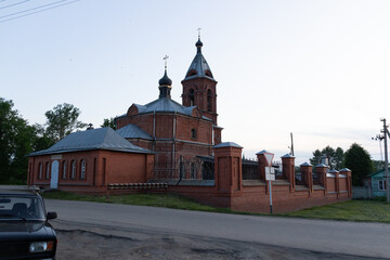 Country landscape with red brick church in summer evening