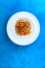 Tasty pasta in big white plate blue background