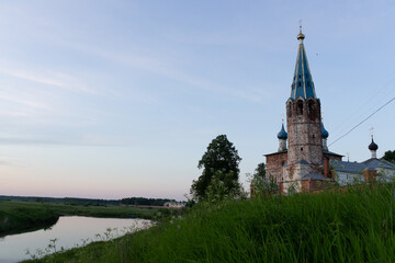 Country landscape in summer evening with old belfry on river side