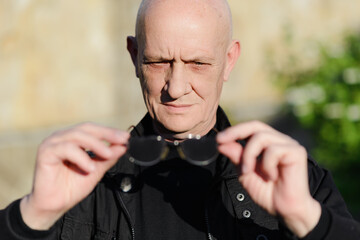 Old man holds vision glasses in his hand. High quality photo