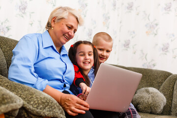 Grandmother with grandchildren using laptop at home