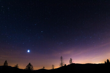 Naklejka na ściany i meble Sunset with stars in the sky and a gradual milky way view of Lysa Hora Czech Republic.