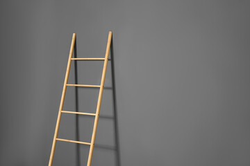 Modern wooden ladder on grey background. Space for text