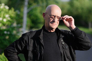 Old bald man looking through the glasses at the camera. High quality photo