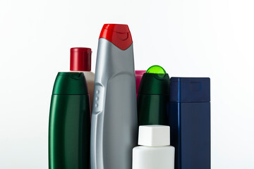 A lot of nameless plastic bottles of different colors from under a cosmetic product on a white...