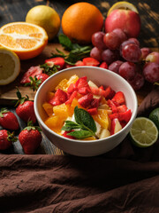 Tasty dessert salad with ice cream and summer fruits assorted mix on table background.