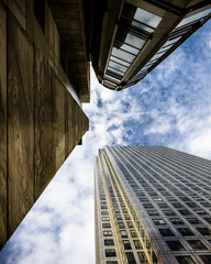 Vertical shot against a marble pillar with office building in the background against a cloudy blue sky