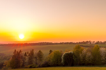 The setting sun over the forested mountain landscape of the Beskydy region, the sun sets beyond the horizon.