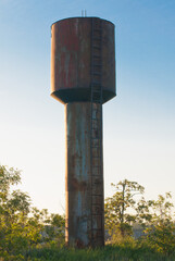 Old rusty abandoned water tower with an iron staircase. abandoned industrial facility