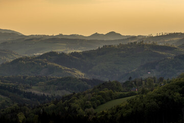 Sunrise over the mountain area covered with fog orange rays penetrate the landscape.