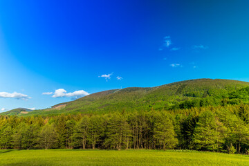Mountainous landscape and Radhost hill during a sunny day with clouds in the sky.