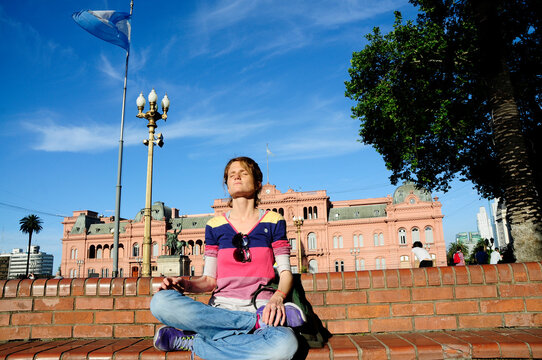 A young woman poses in the city of Buenos Aires with the Presidential Palace in the background.