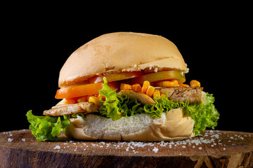Big homemade sandwich with chicken, lettuce, tomato, onion, ham, corn and cheese. Brazilian style.