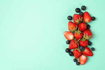 Tasty red strawberry and blueberry on mint background, top view