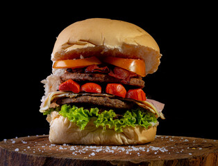 Big homemade burger with two beef burger, lettuce, tomato, sausage, ham, bacon and cheese, AKA...