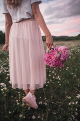 the girl holds a bouquet of pink peonies in her hand