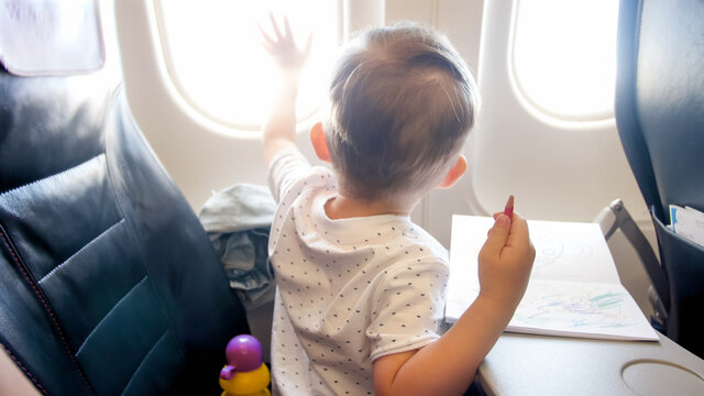 Cute little boy looking out of the window in airplane during flight