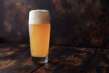A large mug of golden beer stands on a wooden background in a bar