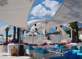 Obraz premium Empty summer beach cafe with white parasols and blue sofas