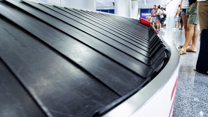 Tourists waiting for their luggage at empty conveyor belt in airport terminal