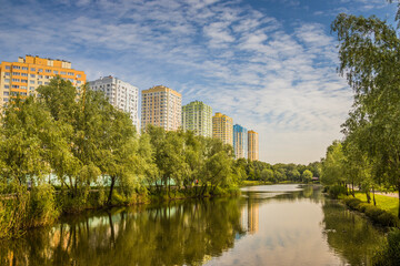 Fototapeta na wymiar Landscape from sity park, Kyiv. Ukraine. Little river, hot summer, bright green trees and high buildings