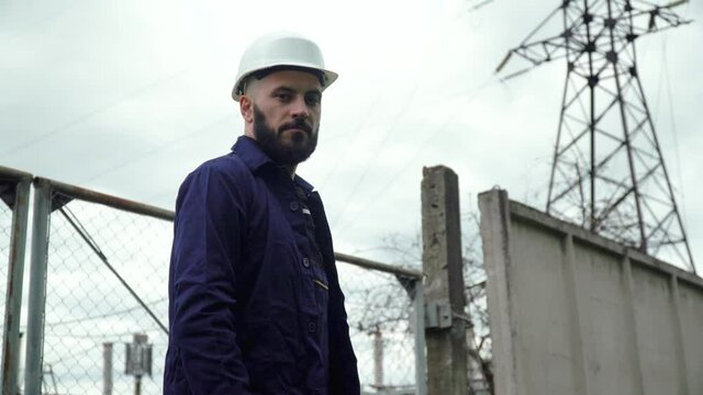 Engineer in special uniform standing with tablet near power station. Energy efficiency conception