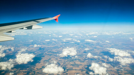 Fototapeta premium Toned image of airplane wing flying above clouds and land