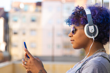 afro american latin girl with mobile phone and headphones on the street outdoors