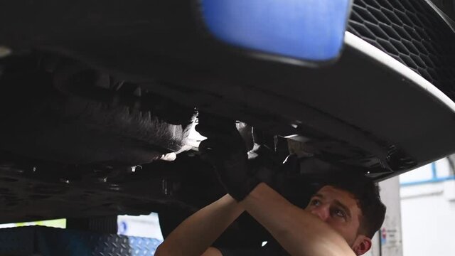 mechanic changing the oil filter and inspecting the underside of a car