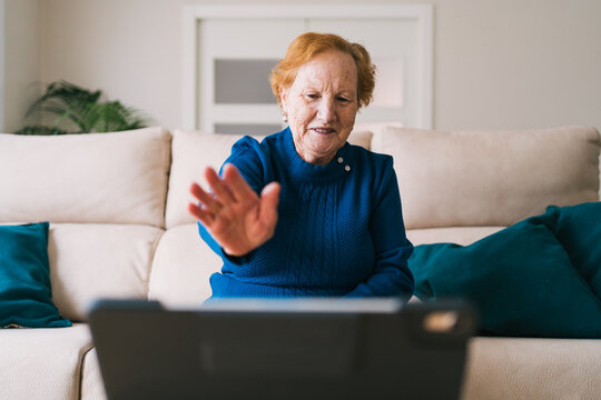 Senior woman communicating with friend during video chat on laptop