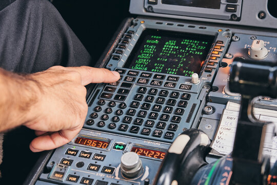 Crop Anonymous Male Pilot Using Keyboard Of Flight Management System In Cockpit Of Modern Aircraft During Flight