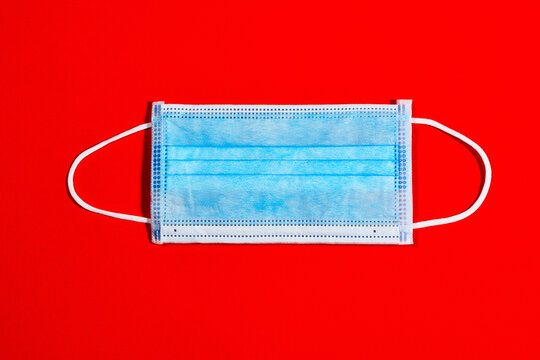 blue single-use mask for virus protection on red background