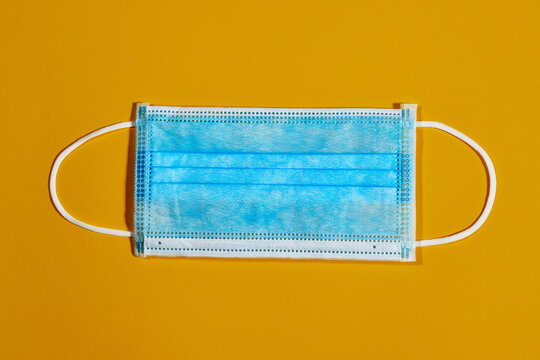 blue single-use mask for virus protection on yellow background