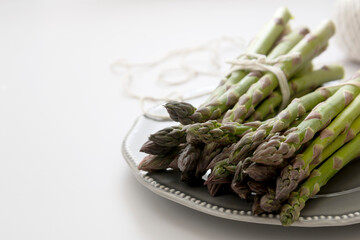 Fresh asparagus on grey plate over white background. Copy space.
